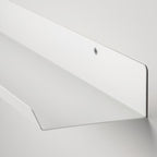 Malmback Display shelf holding picture frames on a modern white wall