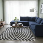 Black and white Rova zigzag rug beneath a round table beside a blue sofa