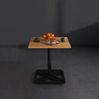 Cubic square table with wood-tone top and black geometric base set for a meal