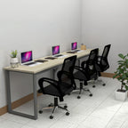 Eclectic three-person workstation with light desktop, laptops and black chairs, angled view