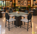 Prism coffee table with a square glass top and dark pedestal surrounded by four chairs in a cafe