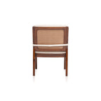 Rear view of the Walden lounge chair showing its woven PVC rattan back panel, wooden frame, and cream cushion strap.